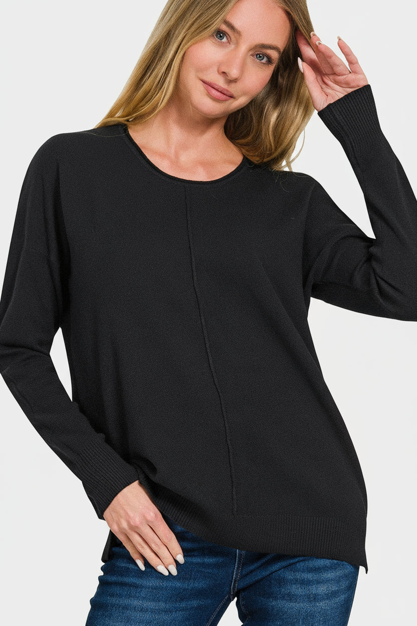 Woman wearing a black front seam sweater and blue jeans on a white background