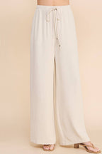Woman wearing oatmeal wide leg pants on a beige background
