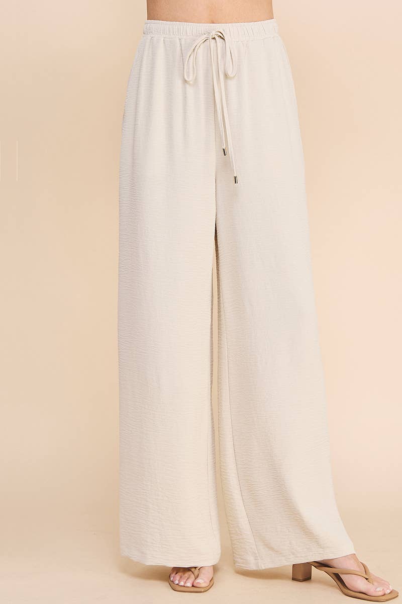 Woman wearing oatmeal wide leg pants on a beige background