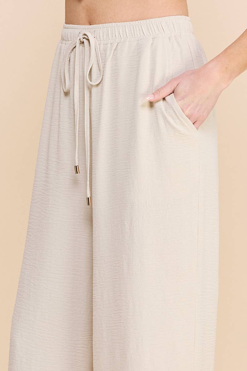 Woman wearing oatmeal wide leg pants on a beige background