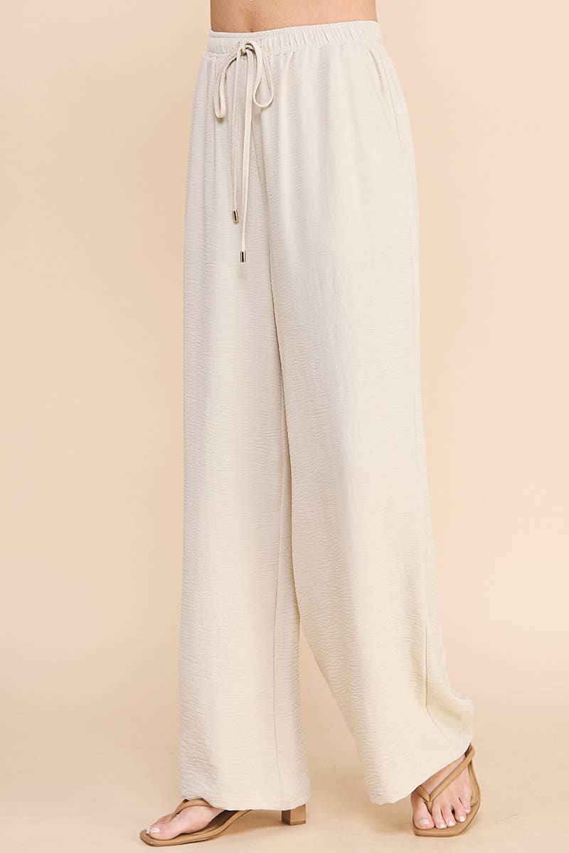 Woman wearing oatmeal wide leg pants on a beige background