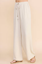 Woman wearing oatmeal wide leg pants on a beige background