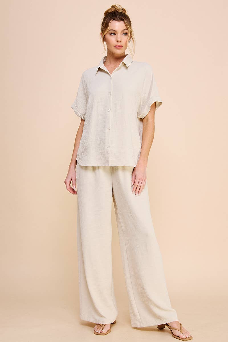 Woman wearing a light-colored shirt and wide-leg oatmeal pants on a beige background