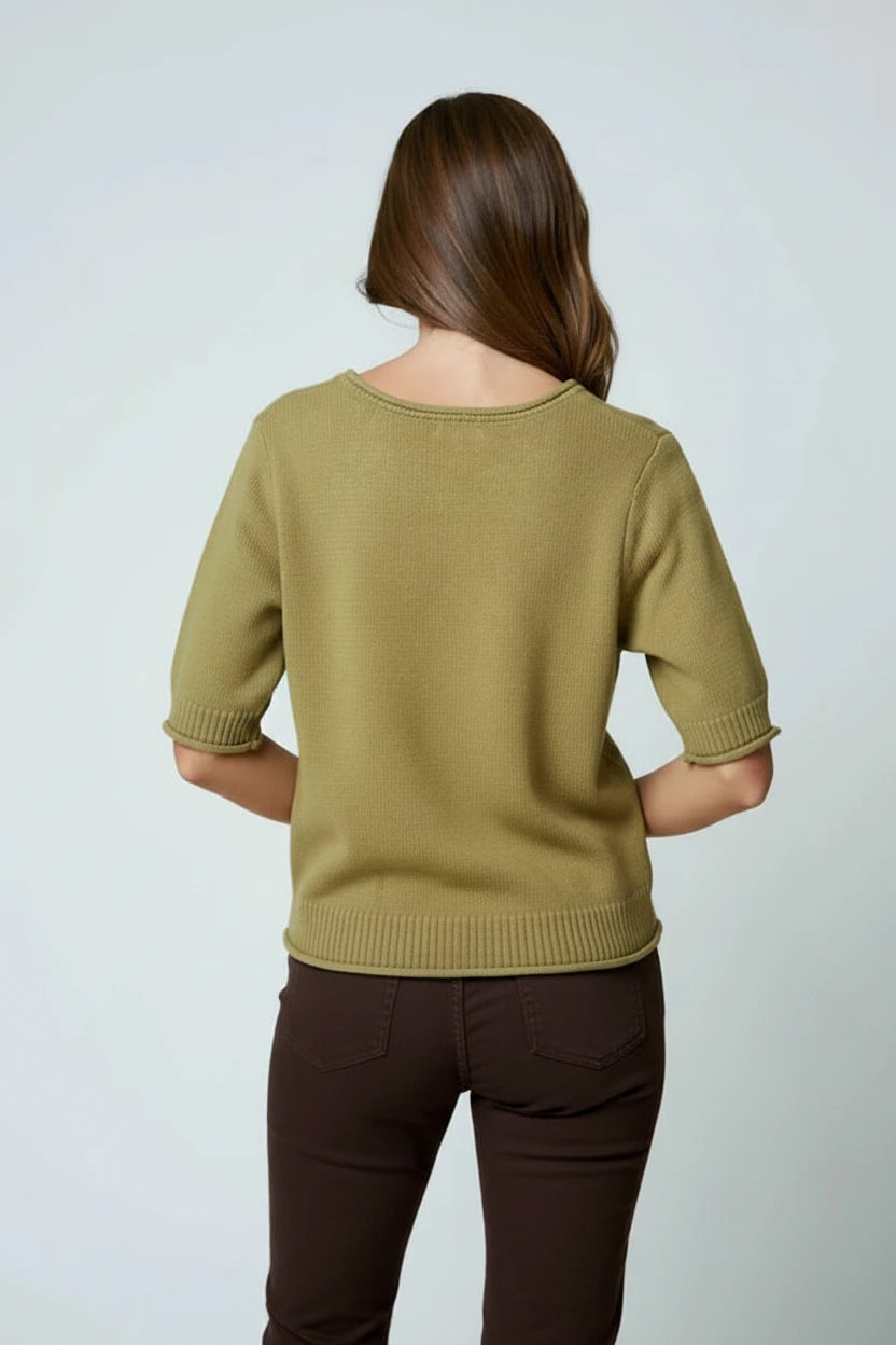 Back view of a woman wearing an olive sweater top and brown shorts on a light gray background