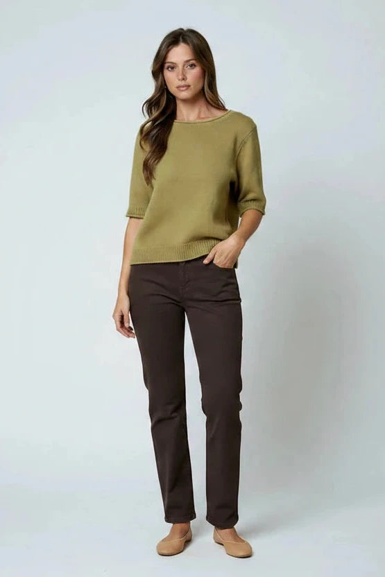 Woman wearing an olive knit top, brown shorts, and tan knee-high boots on a white background