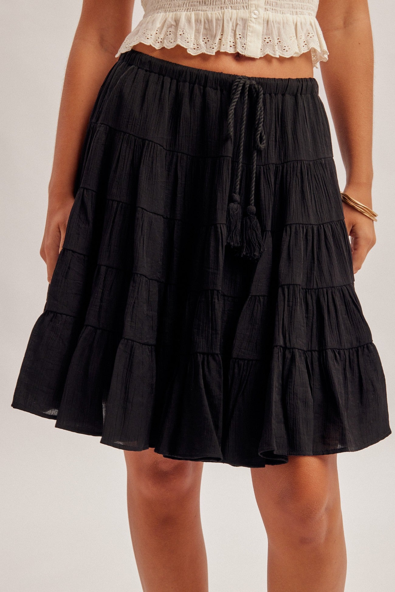 Black tiered skirt with elastic and tie waist worn by a woman on a plain background