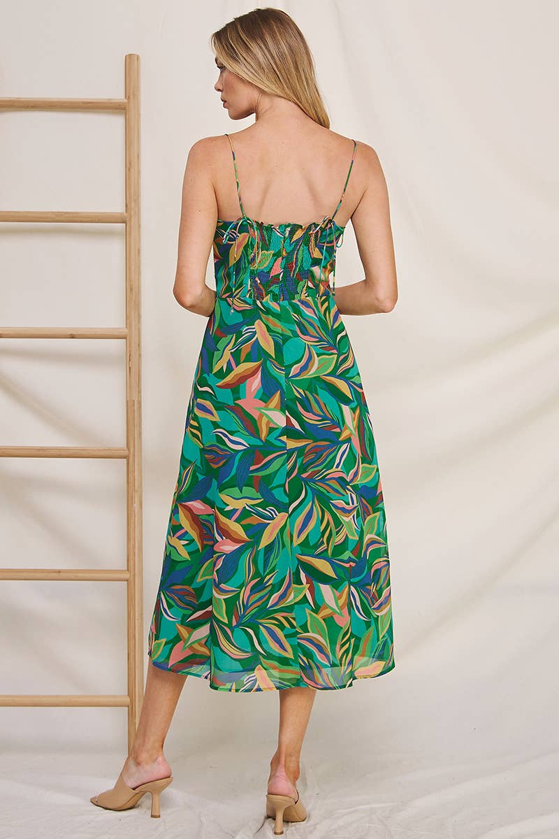 Back view of a woman wearing a colorful tropical print chiffon dress against a neutral background
