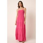 Woman wearing a hot pink maxi dress against a light pink background