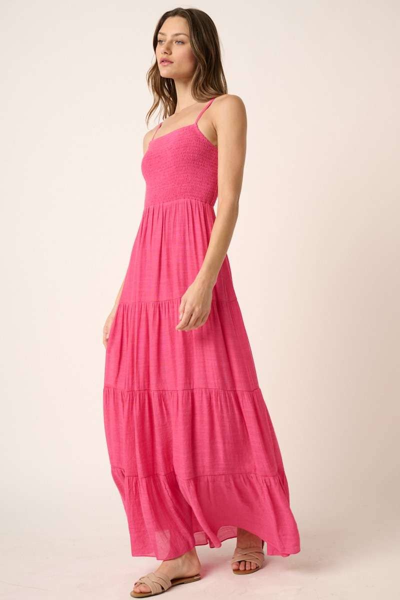 Woman wearing a hot pink maxi dress on a plain background