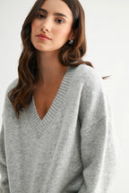 Woman wearing a heather grey knit sweater against a white background