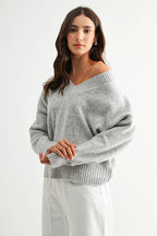 Woman wearing a heather grey knit sweater against a white background