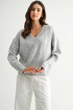 Woman wearing a heather grey knit sweater against a white background