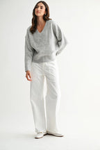 Woman wearing a heather grey knit sweater against a white background