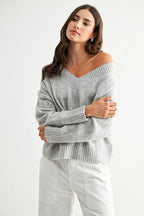 Woman wearing a heather grey knit sweater against a white background