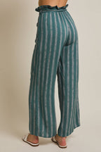 Back view of a woman wearing striped green and cream ruffle top pants with self tie