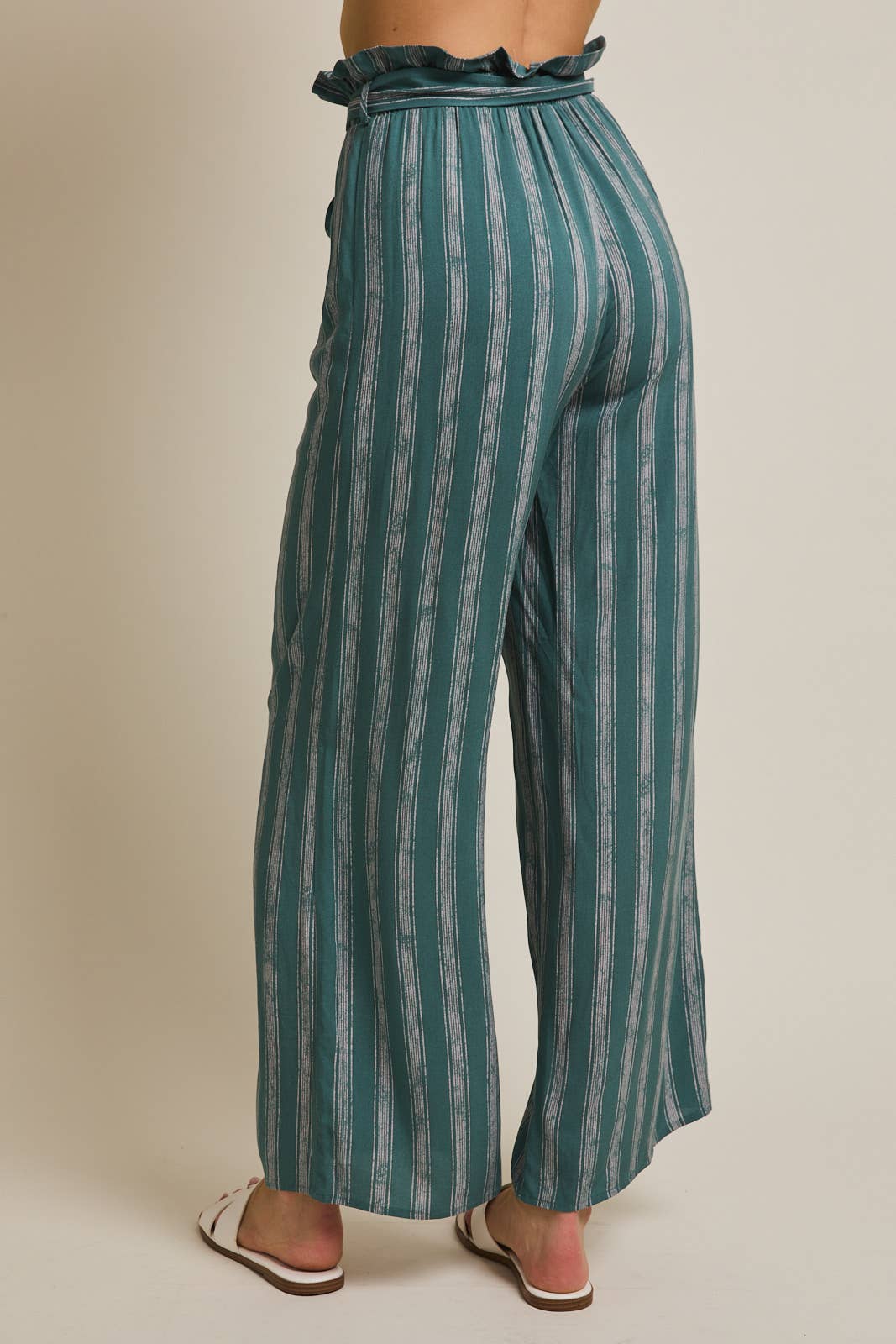 Back view of a woman wearing striped green and cream ruffle top pants with self tie
