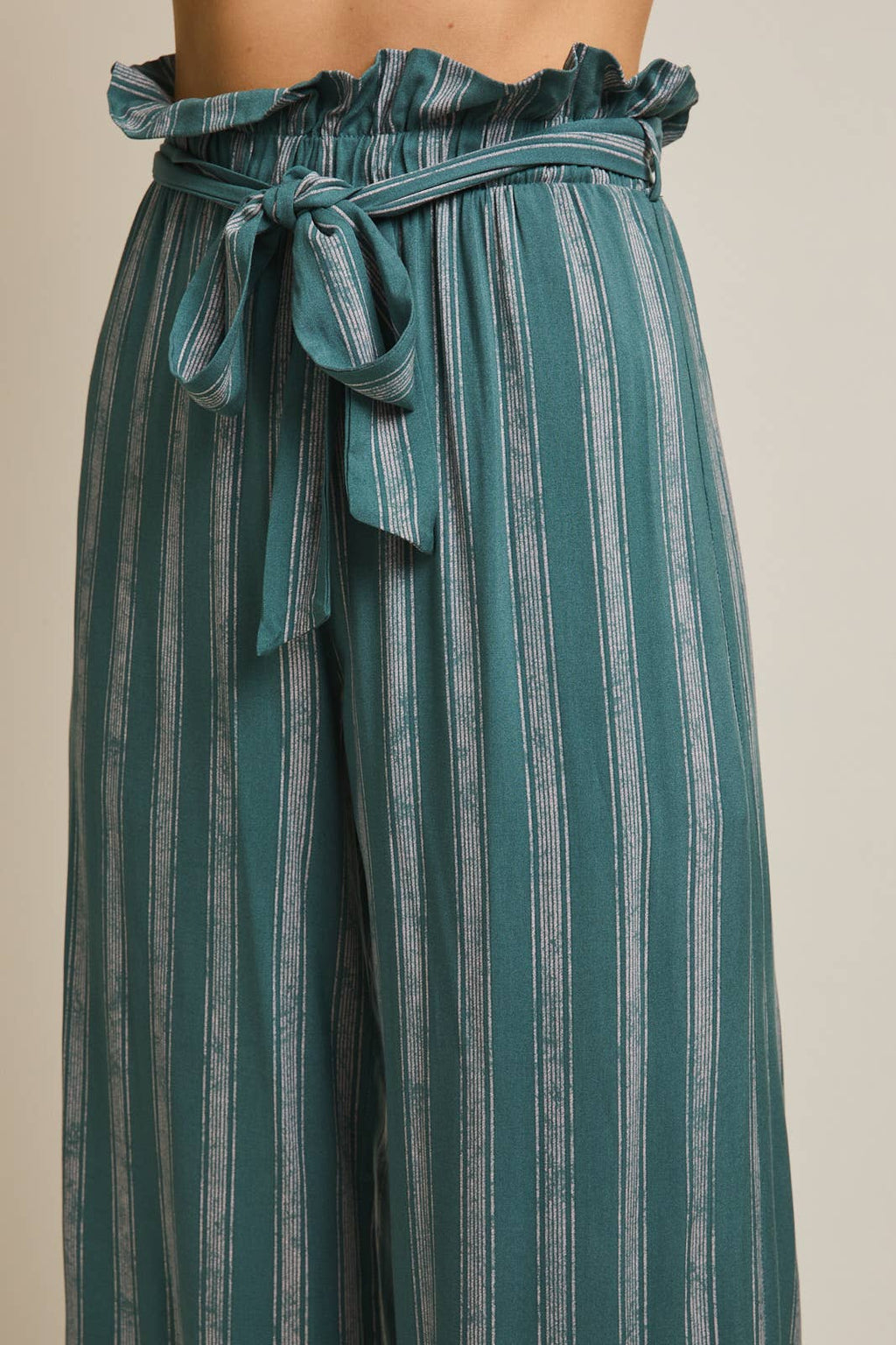 Woman wearing striped green and cream ruffle top pants with self tie