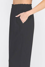 Black wide-leg pants worn by a person on a white background