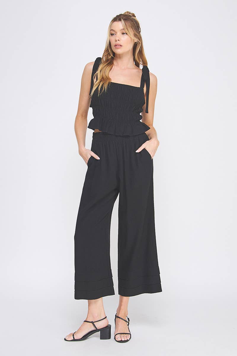 Black wide-leg pants and tank top worn by a person on a white background