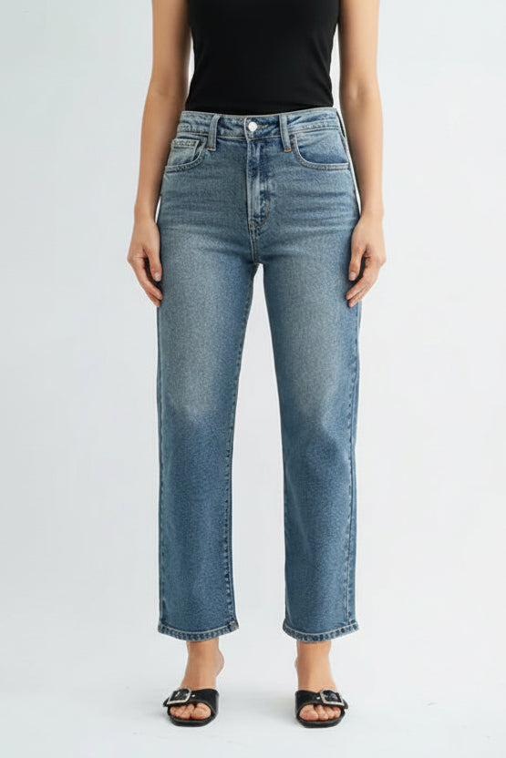 Woman wearing a black tank top and high rise straight leg medium blue jeans on a white background