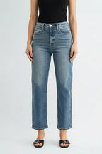 Woman wearing a black tank top and high rise straight leg medium blue jeans on a white background