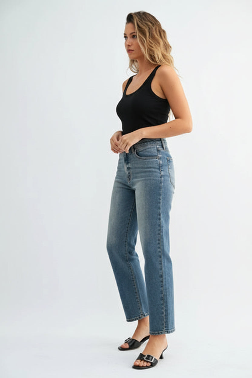 Woman wearing a black tank top and high rise straight leg medium blue jeans on a white background
