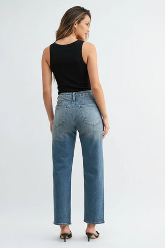 Back view of a woman wearing a black tank top and high rise straight leg medium blue jeans on a white background