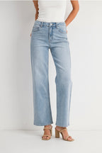 Woman wearing a white tank top and light blue high right straight leg jeans against a white background