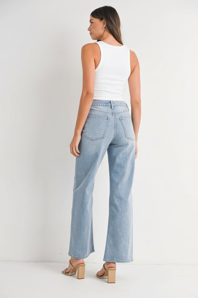 Back view of a woman wearing a white tank top and light blue high right straight leg jeans against a white background