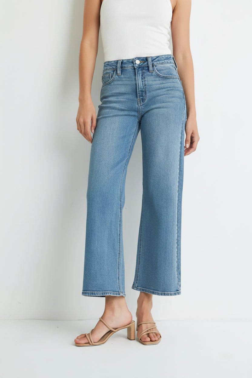 Woman wearing light blue denim high rise slim wide leg jeans on a white background