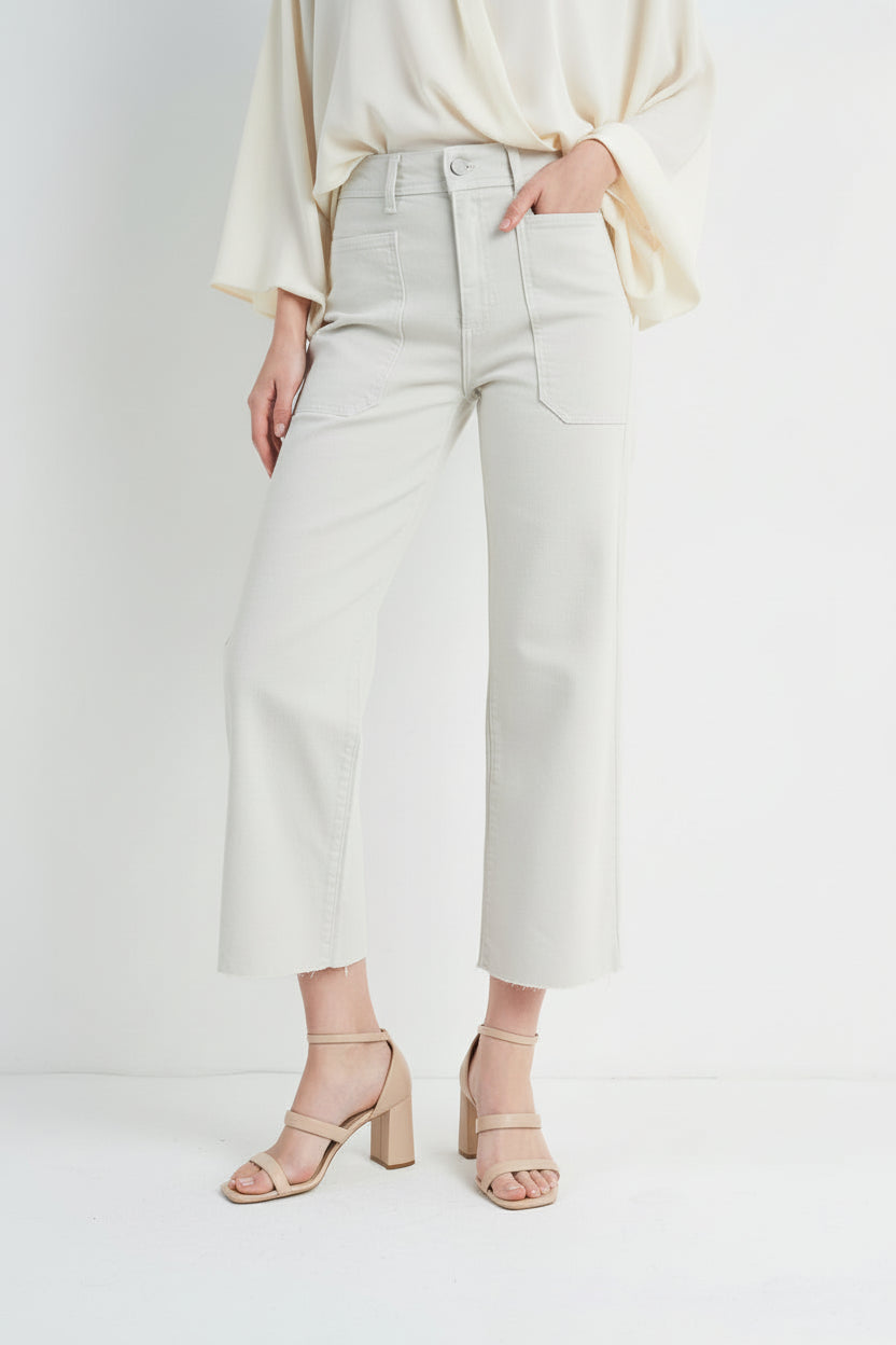 Woman wearing off white jeans and black boots on a white background