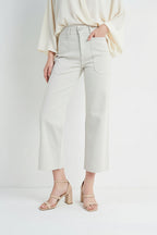 Woman wearing off white jeans and black boots on a white background