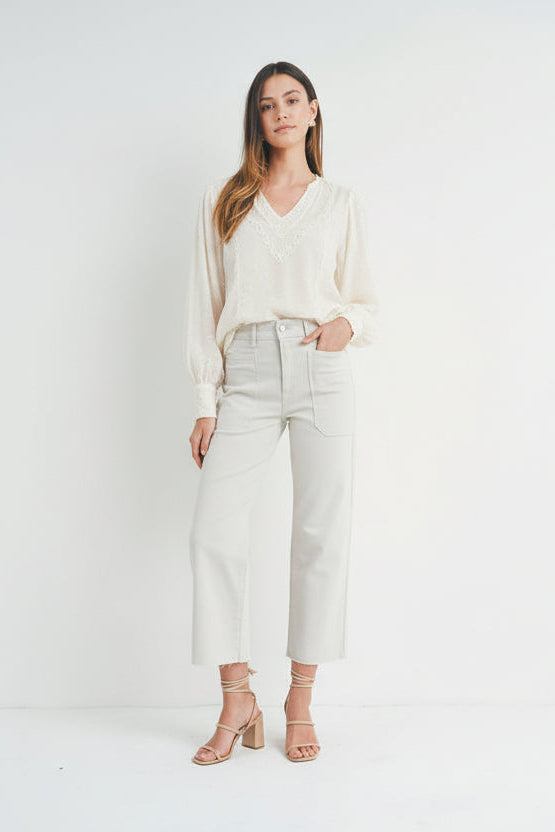 Woman wearing off white jeans, black sweater and black boots on a white background