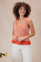 Woman wearing an orange and white  striped crochet knit tank top against a beige background