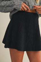Woman wearing a black knit mini skirt on a beige background