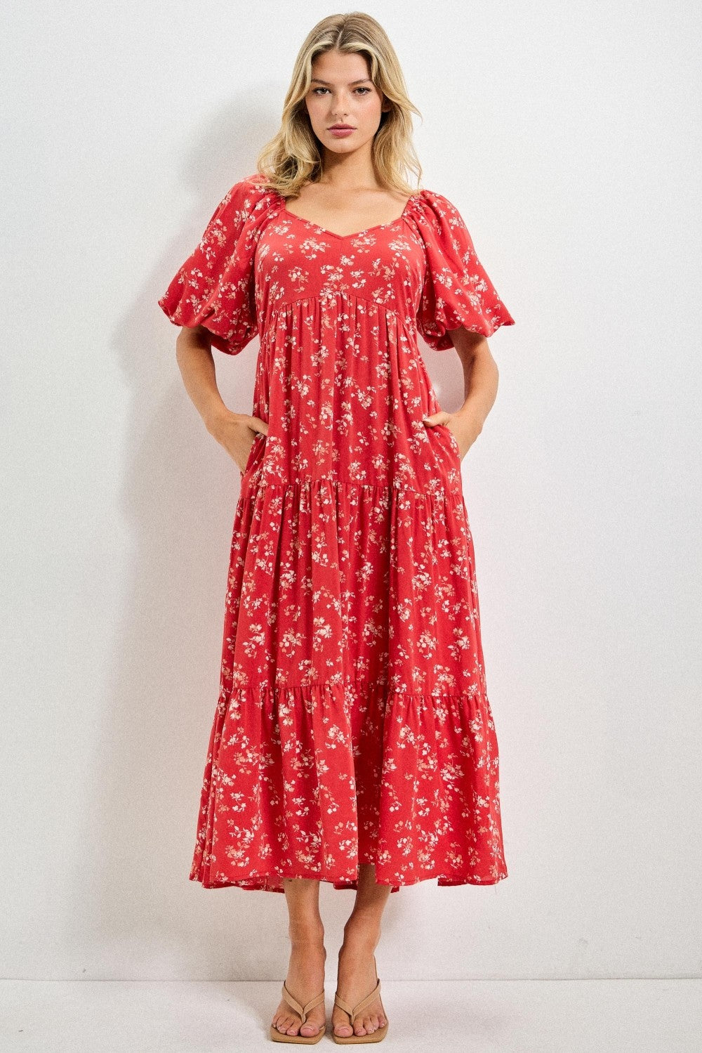 Woman wearing a red floral dress against a white background