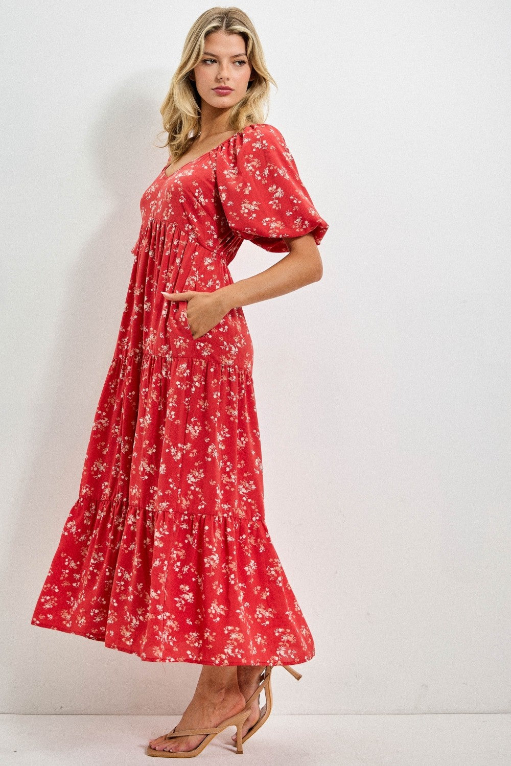 Woman wearing a red floral dress against a white background