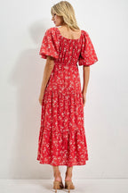 Woman wearing a red floral dress against a white background