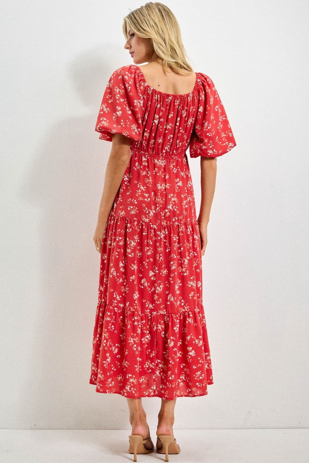 Woman wearing a red floral dress against a white background