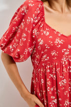 Woman wearing a red floral dress against a white background