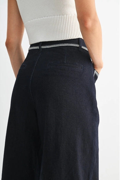 Women's dark denim wide-leg pants with a white top on a plain background