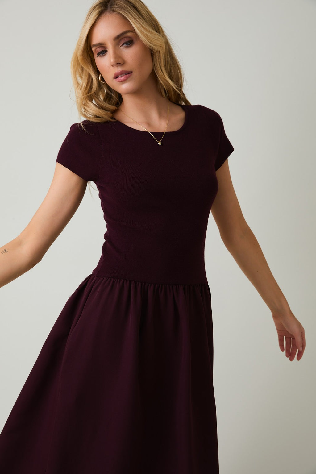 Woman wearing a plum midi dress against a plain background
