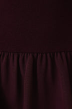 Close-up of a plum knit top and woven fabric skirt with matte satin texture.