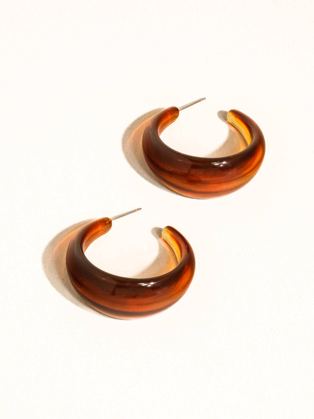 Pair of brown resin hoop earrings with 18k gold-plated non-tarnish posts on a white background