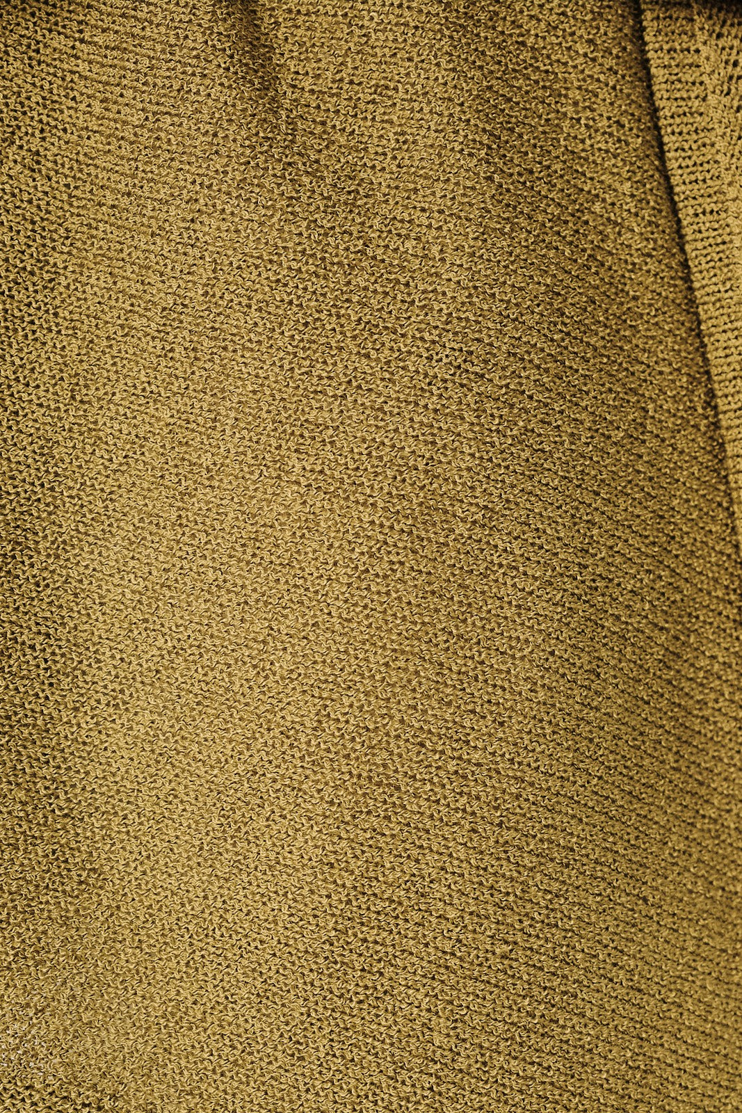 Close-up of a textured knit fabric in a green knit showing the detailed weave pattern 