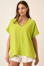 Woman wearing a lime top and white shorts on a beige background