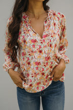 Woman wearing a floral blouse outdoors with greenery in the background