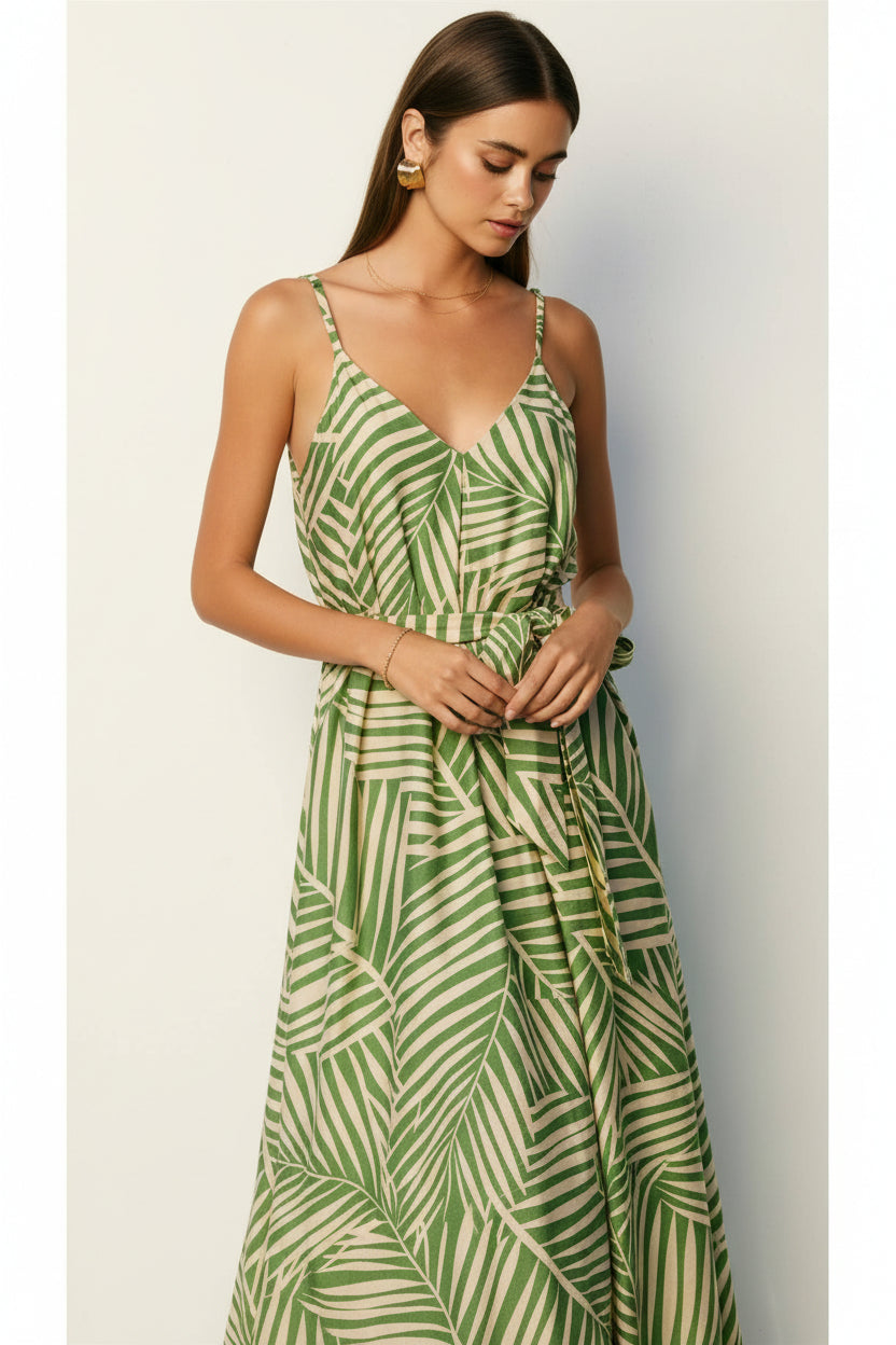 Woman wearing a sage and cream leaf patterned maxi dress against a plain background