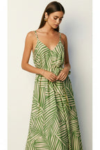 Woman wearing a sage and cream leaf patterned maxi dress against a plain background