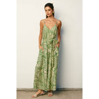 Woman wearing a sage and cream leaf patterned maxi dress against a plain background